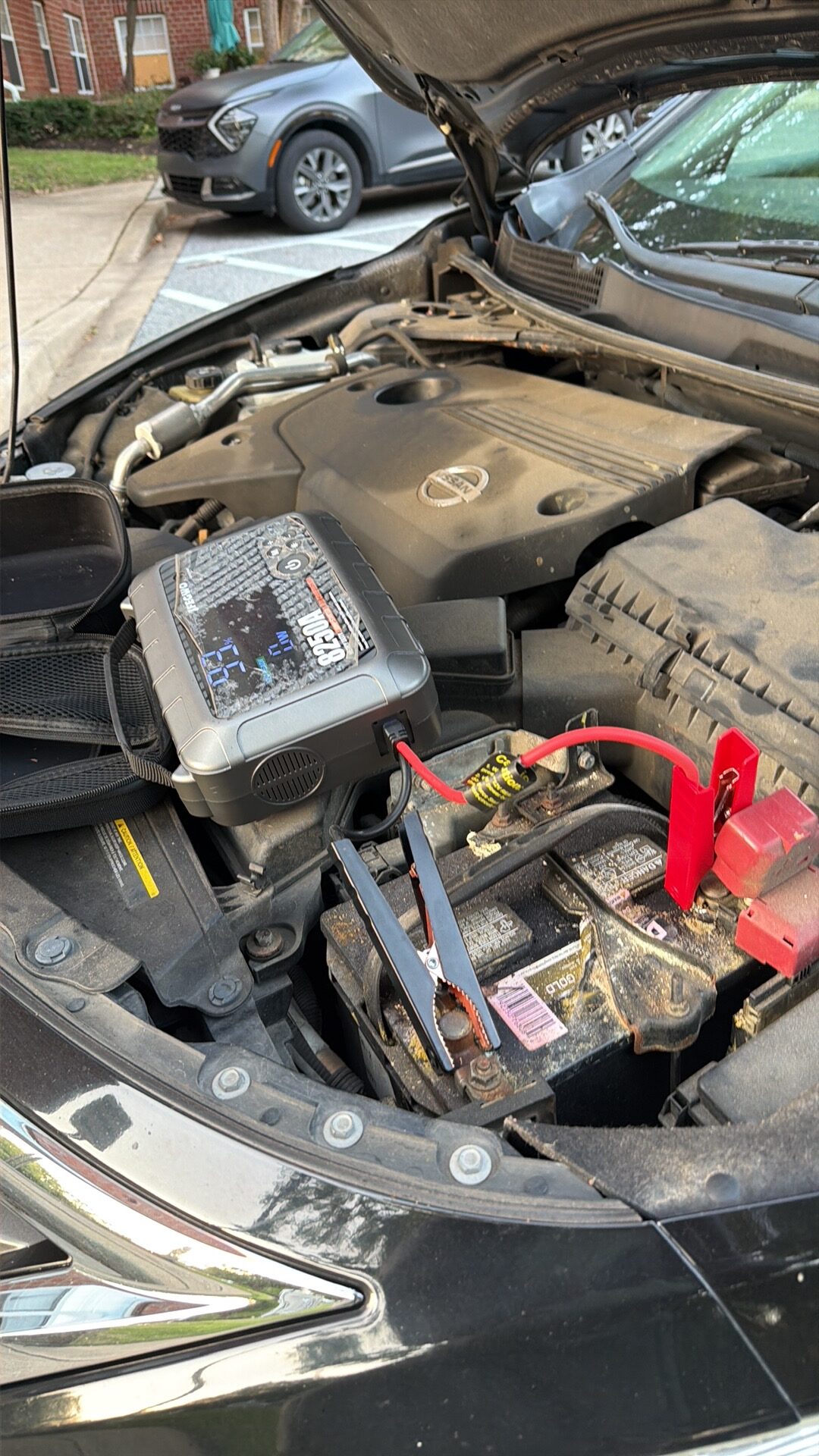 Close view of the 8250A-labelled portable starter and battery connections in the Nissan Altima