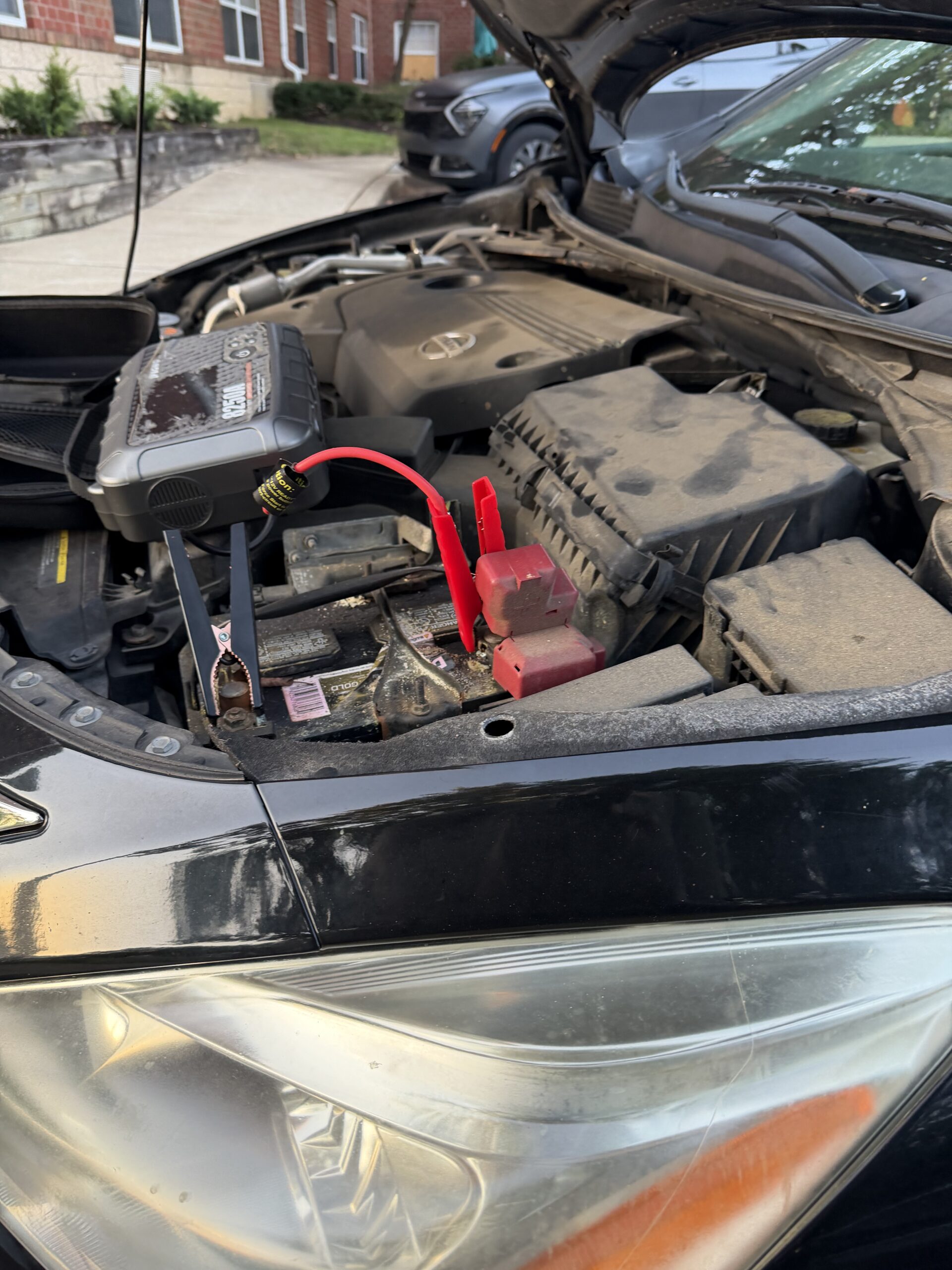Portable jump starter and battery clamps under the Nissan Altima bonnet on Cantata Court in Reisterstown