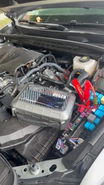 Automotive tester connected in a Toyota Camry engine bay during mobile battery service in Laurel Maryland