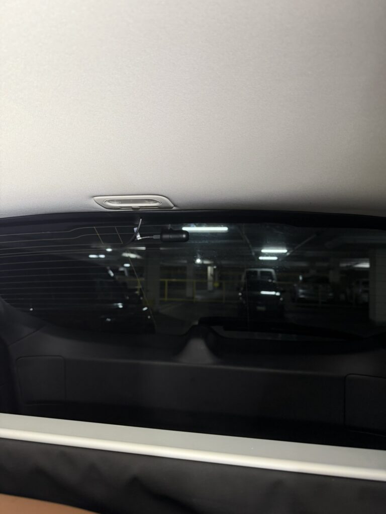 Rear dash camera mounted high on the Subaru Outback rear window, with a short cable section visible above it.
